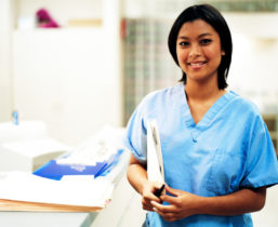 A dark skinned woman holding a folder of documents in a clinical setting