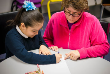 A woman helping a child work with pencil and paper