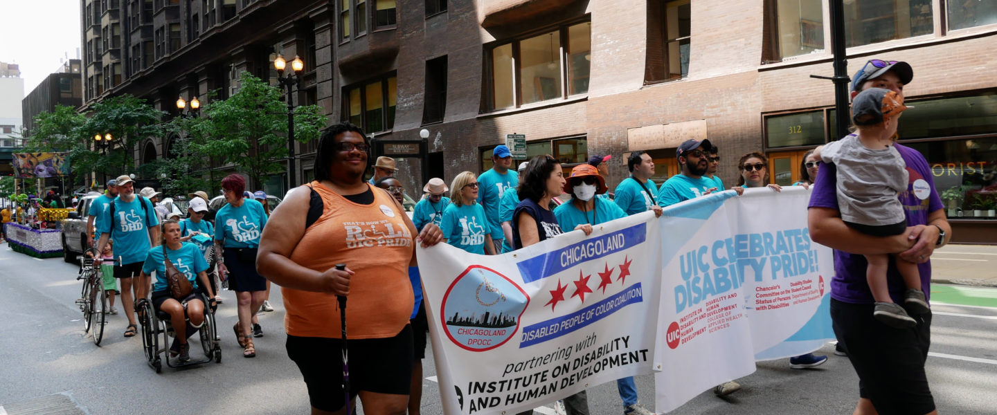 a group of people in a parade holding a banner wearing IDHD shirts