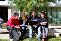 A group of UIC students gather around a laptop screen while sitting outside
