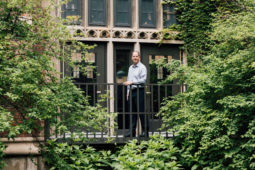 David Scalzitti stands on an elevated balcony surrounded by green treeas and schrubs
