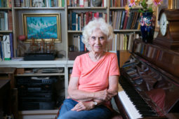 Phyllis Bowen sits next to a piano in her home library