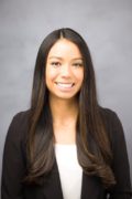 Image of a women with long dark brown hair wearing a black blazer and white undershirt smiling and looking into the camera