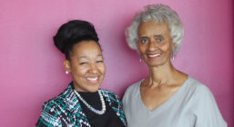 Briana Bonner and Winifred Scott standing in front of a bright pink background