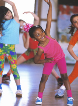 A group of girls are stretching as part of an exercise routine