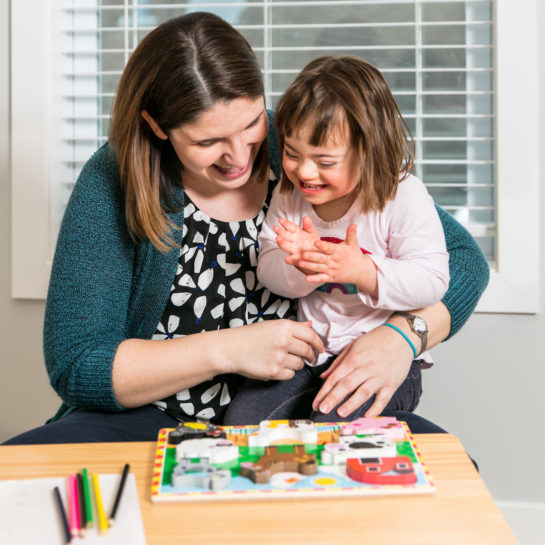 A occupational therapist holds a child client during a therapy session